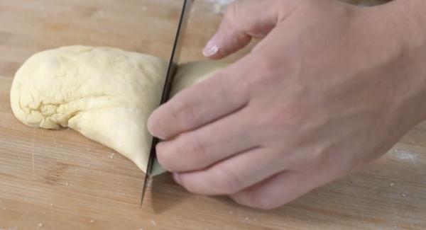 Nachdem der Teig in der Küchenmaschine geknetet ist, den Teig rausnehmen und in einer Schüssel an einem warmen Ort 60 Minuten gehen lassen. Den aufgegangenen Teig auf einem Brett nochmal mithilfe von Mehl durchkneten. Anschließend den Teig länglich Formen und in vier gleich große Stücke schneiden.