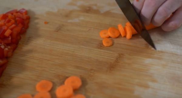 Die Möhren in Scheiben und die Paprika in Würfel schneiden.