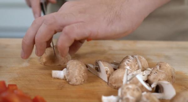 Zwei Paprika und 100 g Champignons klein schneiden und zwei Knoblauchzehen schälen.