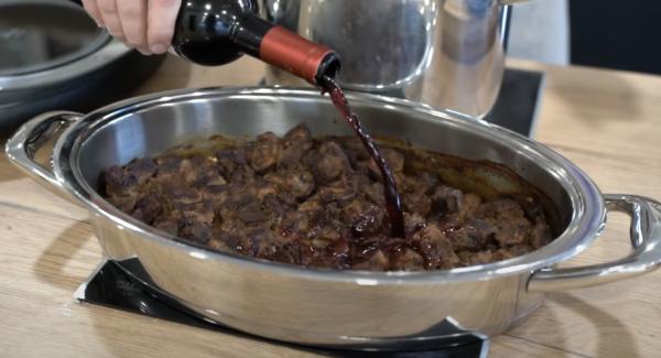 Den Rindergulasch aus dem Backofen holen und den restlichen Wein dazugeben.