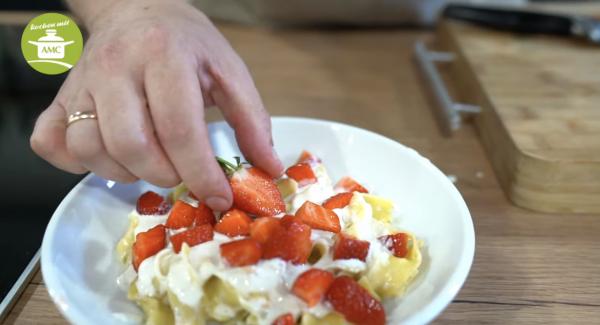 Nudeln mit der Soße vermischen und mit Erdbeeren und Schokolade dekorieren.